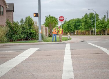 two workers standing across street crosswalk